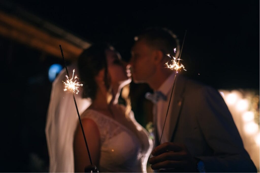 Sparklers wedding send off (1) A bride and groom about to kissing holding sparklers