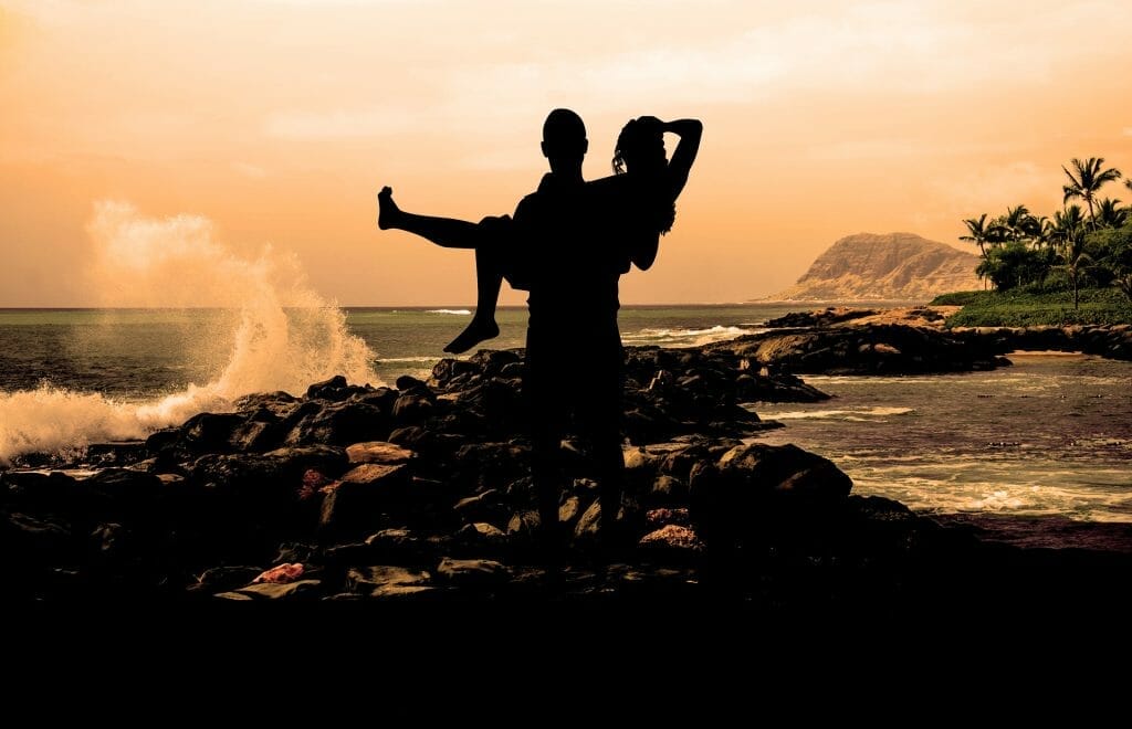 Silhouetted couple on rocks in front of sea