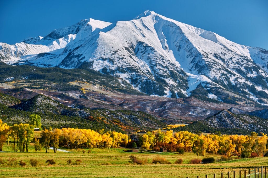 Snowy Colorado mountain with green field