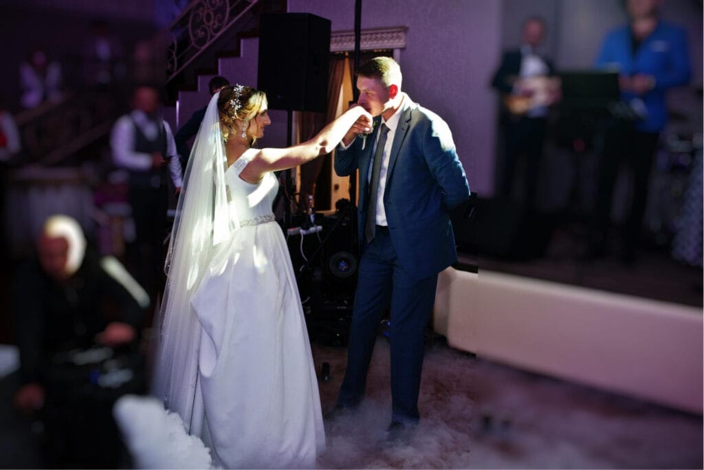 Wedding dance songs (2) A groom kissing a bride's hand about to dance